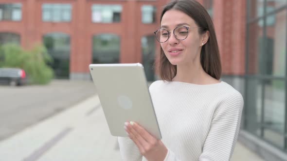 Video Call on Tablet by Young Woman while Walking on Street