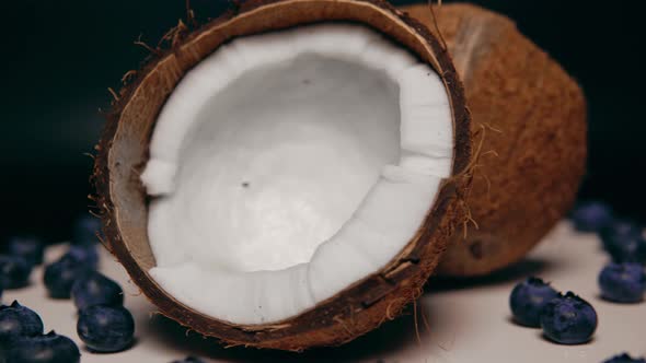 Two Halves of Coconut with White Pulp Inside and the Handful of Berries