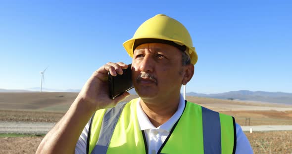 Male engineer talking on mobile phone in the wind farm