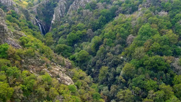 Aerial Circle Dolly Around Forest Ravine To Reveal Fervenza do Toxa Waterfalls In Distance