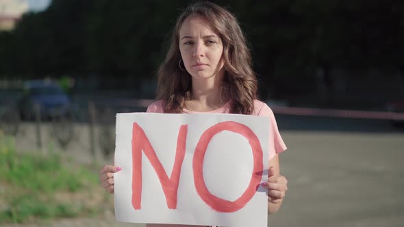 Beautiful Young Woman with No Banner Standing in Sunlight Outdoors. Brunette Caucasian Activist