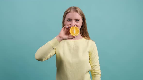 Funny Cheerful Girl Holding Half of Orange Against Her Mouth.