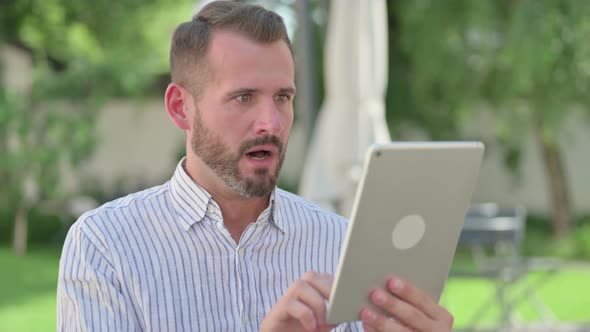 Outdoor Portrait of Middle Aged Man Reacting to Loss on Tablet