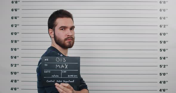 Mugshot of Male Criminal Person Turning Head and Looking to Camera While Standing Aside