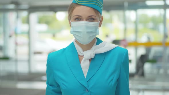 Young Stewardess in Uniform and Face Mask Looking at Camera and Smiling. Portrait of Positive