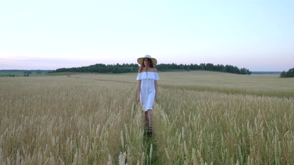 Beautiful Woman Goes to Field of Ripe Golden Wheat