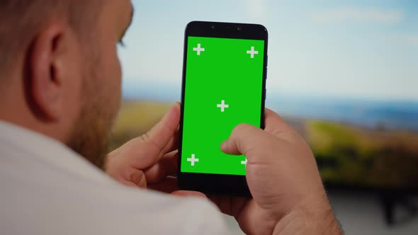 Man Using Smartphone with Green Screen for Copy Space Close up Chroma Key Mockup.