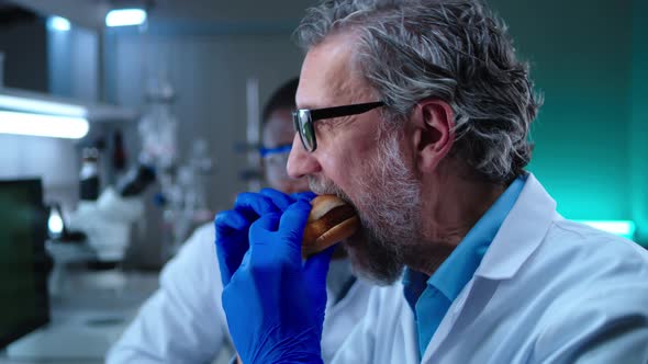 Man Tasting Burger with Lab Grown Meat Near Colleague