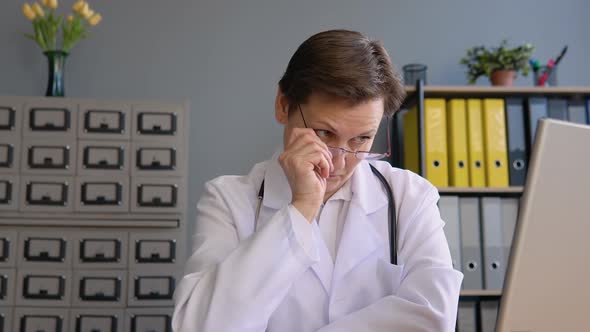 Portrait of a Senior Positive Female Doctor 50s Sitting in Her Office with a Laptop