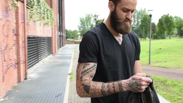 young beautiful bearded man outdoor wearing leather jacket walking in the city