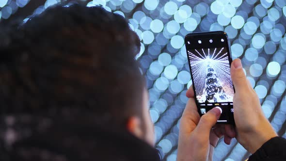 Man Take Photo on the Phone in the Main City Christmas Tree on Christmas Celebrations