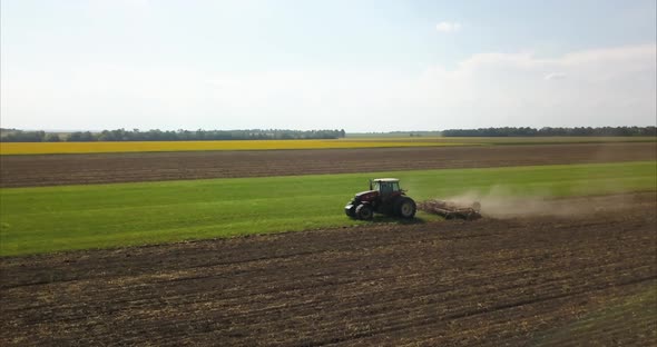 drone side footage of tractor cultivating soil // 4k