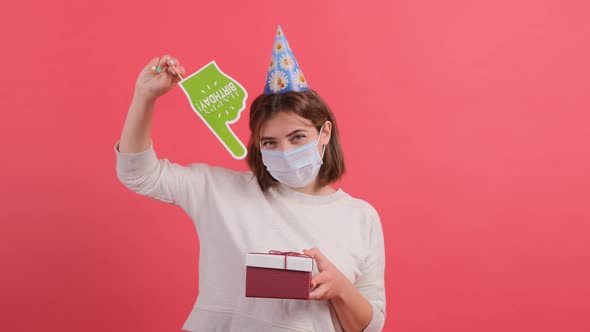 Woman with Medical Mask on Face Showing with a Cardboard Finger at the Gift Box.