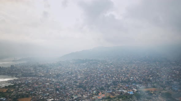 Aerial hyperlapse going backwards over downtown of Freetown Sierra Leone during the day with landfil