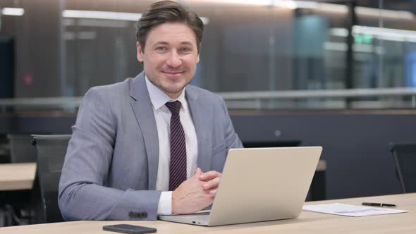 Middle Aged Businessman with Laptop Smiling at the Camera 