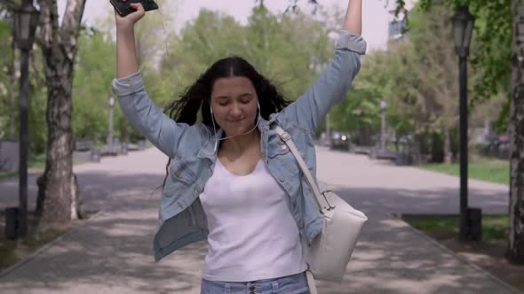 Happy Funny Girl Walking Down the Street and Dancing While Listening To Music on Headphones