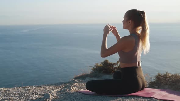 Woman Sits Lotus Yoga Position on Mat and Meditates Outdoors, Slow Motion