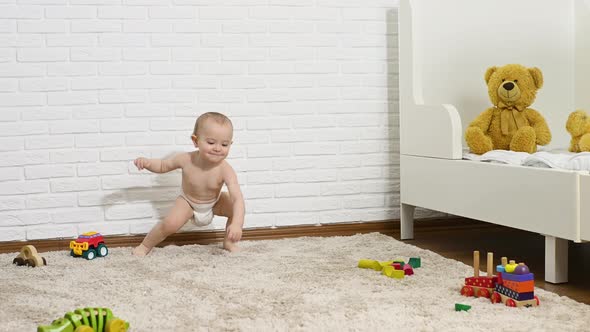 a Baby Boy in a Disposable Diaper Takes the First Steps Barefoot