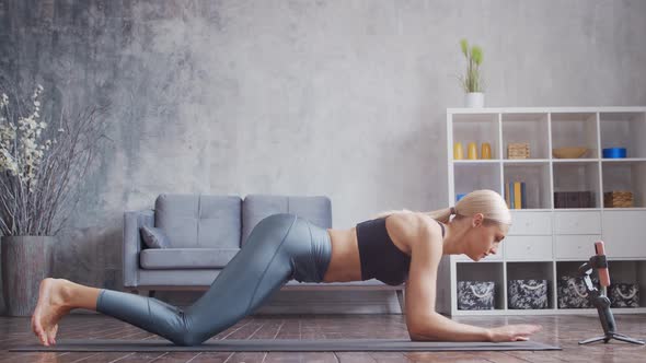 Young and sporty girl in sportswear is doing exercises in home interior.