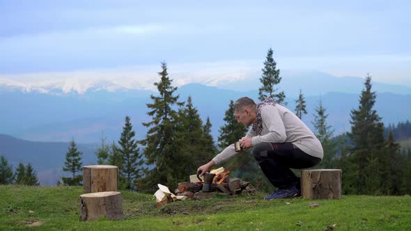 A Man Near a Fire in the Mountains