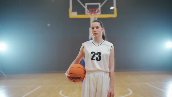 Portrait of a Young Female Basketball Player Holding a Ball in Her Hands and Looking at the Camera