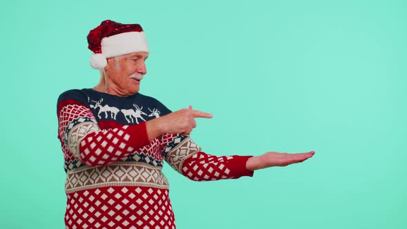 Grandfather in Christmas Deer Sweater Showing Thumbs Up and Pointing at on Blank Advertisement Space