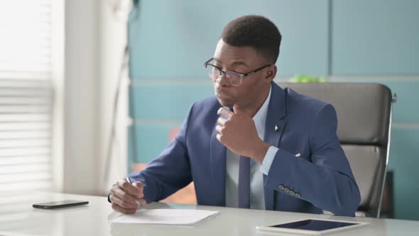 Young African Businessman Reading Reports While Sitting in Office