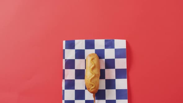Video of corn dog with mustard on a red surface