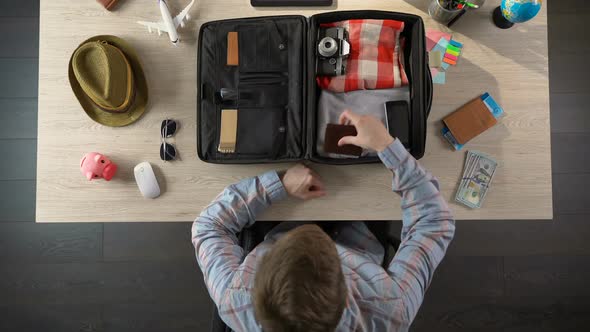 Man Carefully Packing Suitcase for Travel, Taking Money and Documents