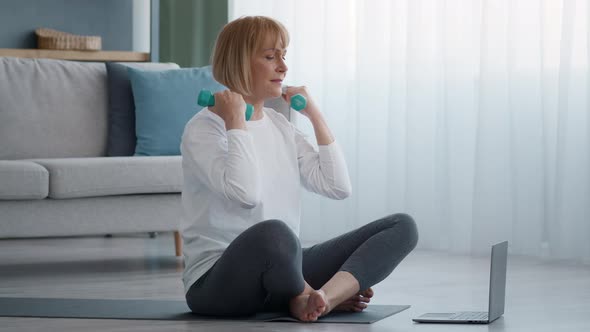 Sporty Senior Lady Exercising With Dumbbells At Laptop At Home