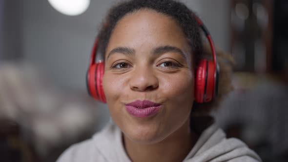 Headshot Portrait of Young Beautiful African American Woman Turning on Music in Headphones and