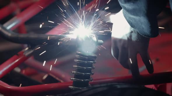 Bright light being cast from welding metal together on vehicle suspension