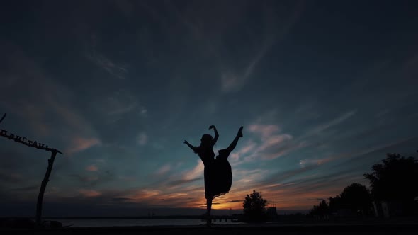 Silhouette of a Ballerina Against the Sunset Sky. the Girl Beautifully Dances Standing on Tiptoes