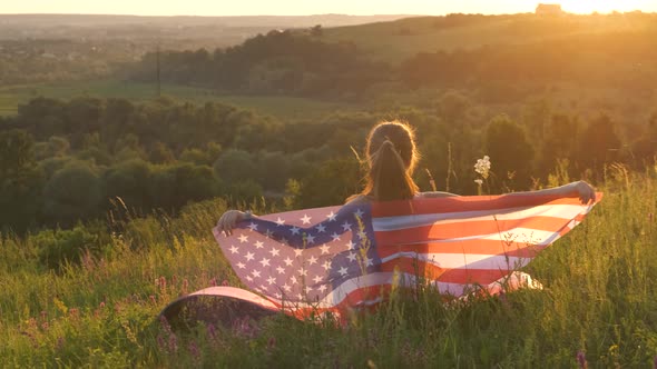 Happy woman with USA national flag outdoors at sunset. Positive girl celebrating United States