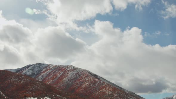 Clouds moving over snow capped mountain covered in Fall foliage