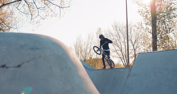 Professional Stunt Cyclist Man Dressed in Loose Clothing Rides Bmx Up Ramp Leaning Wall Hovers