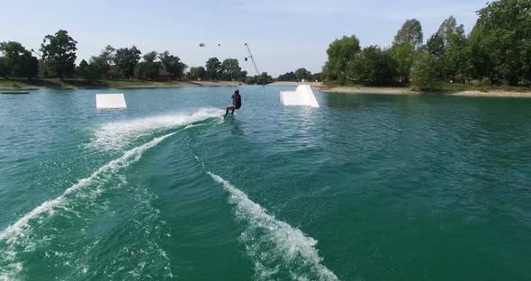 Back view of man jumps over the kicker at wake park