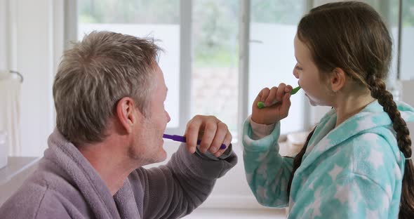 Father and daughter brushing off their teeth