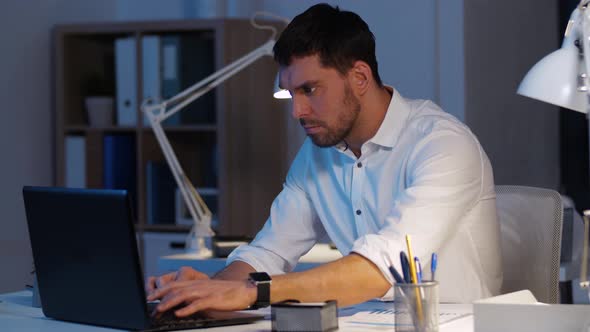 Businessman with Laptop Working at Night Office 