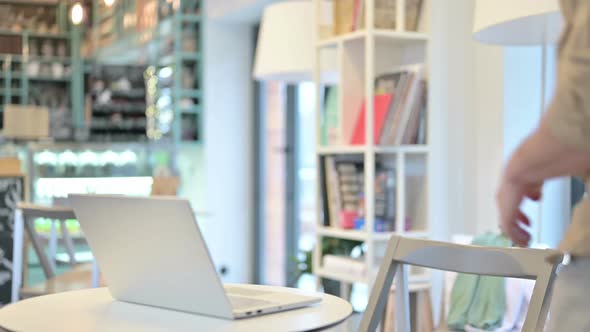 Man Sitting in Cafeand Opening Laptop