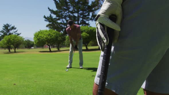 Caucasian senior man practicing golf at golf course on a bright sunny day