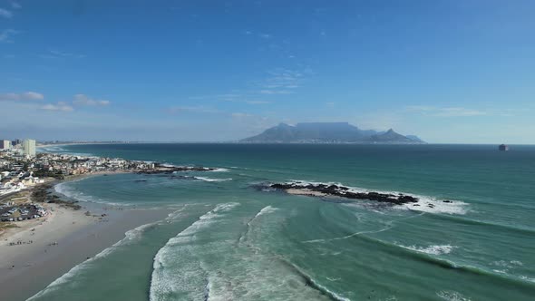 ocean waves and Table Mountain at Big Bay Beach in Cape Town, aerial