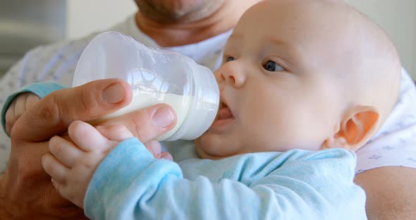 Father feeding milk to his baby boy at home 4k