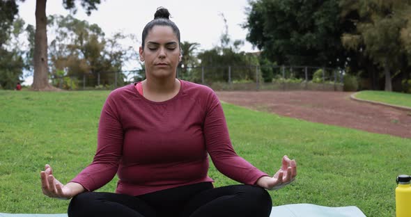 Young curvy woman doing yoga exercises outdoor