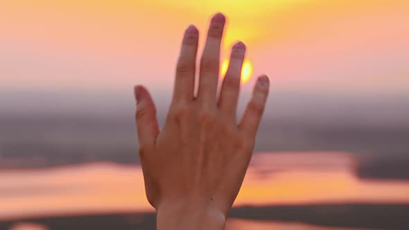 Hand of Young Woman on a Background of Sunset Sky