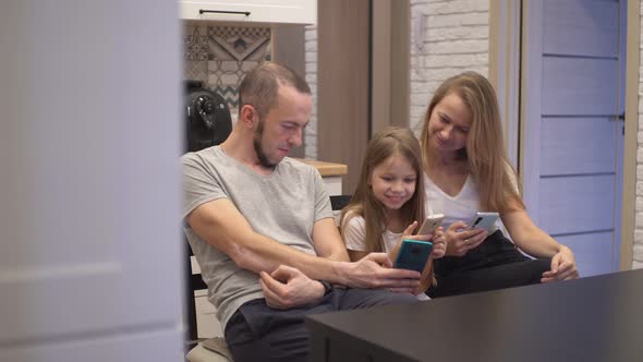 Mom Dad and Daughter Look at Smartphones