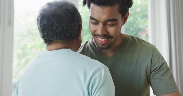 Biracial young man smiling and embracing father at home