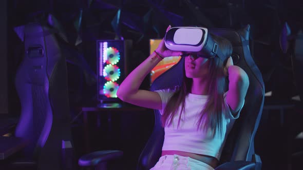 Girl Gamer Putting on a VR Glasses and Looking Around in Neon Lighting