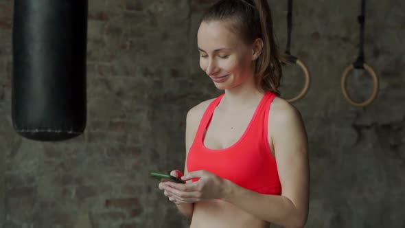 Portrait of Personal Trainer Woman Using Smartphone in Fitness Gym