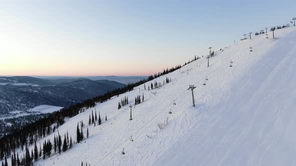 Modern Ski Resort Chairlift Moves Over Tracks Against Forest